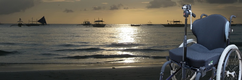 Photo of wheelchair with camera mount on a beach at sunset